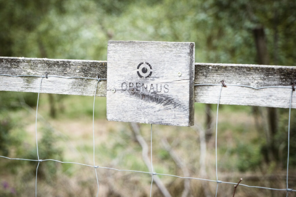 Holzschild Weingut Obenaus am Zaun vor dem Weingarten